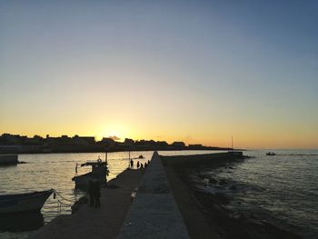 Pier over sea against clear sky during sunset