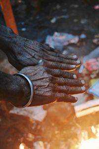 Cropped image of hands warming over bonfire