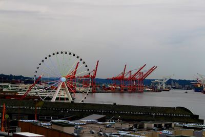 Ferris wheel by river against sky in city