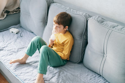  boy sits with an inhalation mask during cough and bronchitis. treatment with an inhaler at home