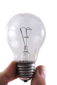 Close-up of hand holding light bulb against white background