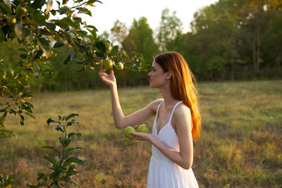 Young woman standing by tree
