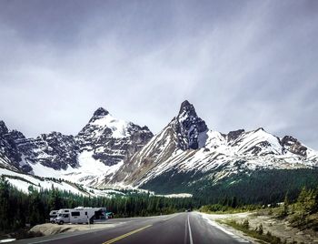 Road amidst snowcapped mountains against sky