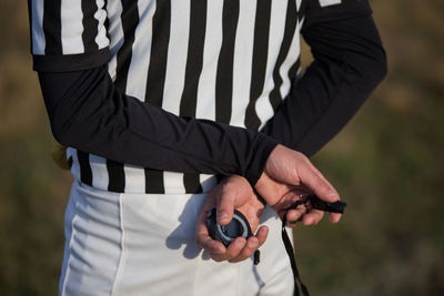 Midsection of referee holding whistle and stopwatch