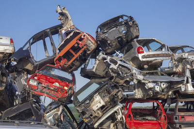 Low angle view of abandoned cars in junkyard against sky