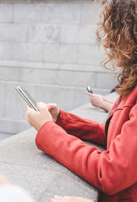 Side view of mature woman using smart phone while standing by retaining wall