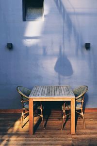 Empty chairs and table against wall