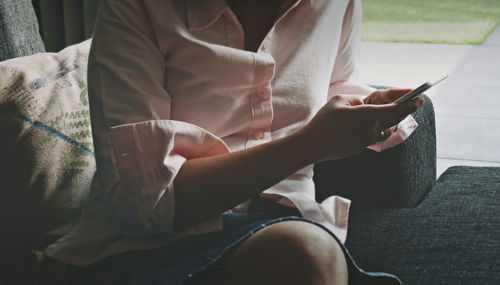 Low section of woman reading book while sitting on sofa