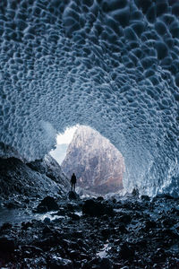 Rear view of silhouette person standing in frozen cave