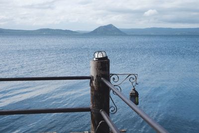 Close-up of railing by sea against sky