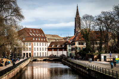 Arch bridge over canal amidst buildings against sky