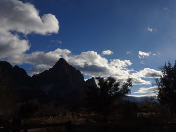 Low angle view of trees and mountains against sky