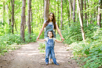 Full length portrait of smiling girl in forest