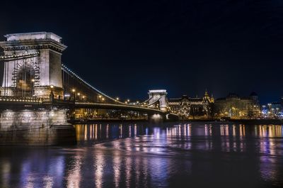 Illuminated bridge over river at night