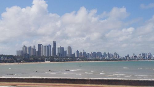 Sea by cityscape against sky