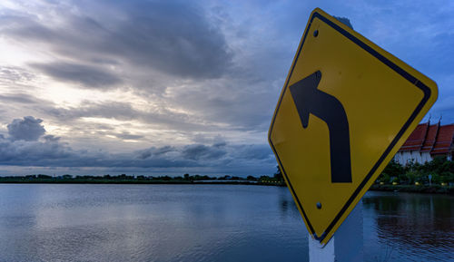 Information sign by road against sky during sunset