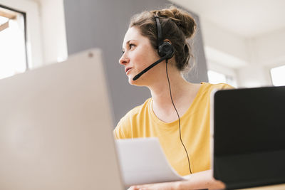 Female entrepreneur talking through headphones while looking away