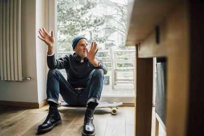 Cool senior man sitting on longboard, gesturing and talking