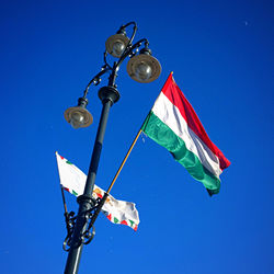 Low angle view of hungarian flag on street light against sky