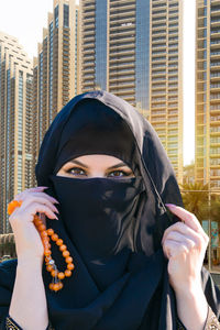 Portrait of beautiful woman in city against buildings