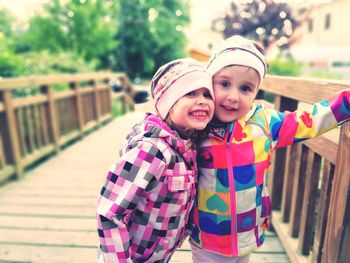 Portrait of smiling girls standing on footbridge