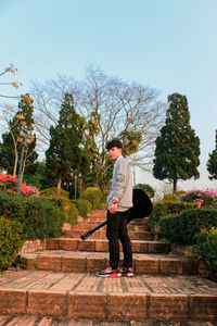 Low angle view of young man holding guitar while standing on staircase 