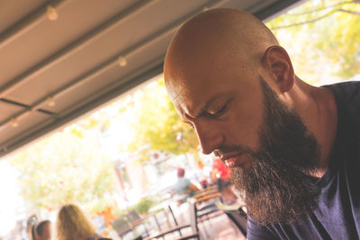 Close-up of young man looking down while sitting in cafe