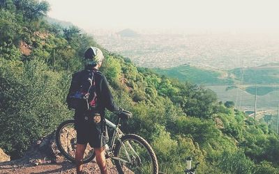 Rear view of man riding bicycle on hill