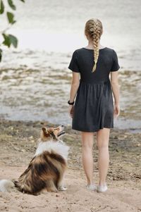 Rear view of woman and dog on beach