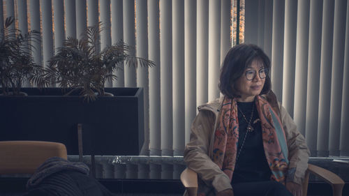 Young man looking away while sitting on sofa at home