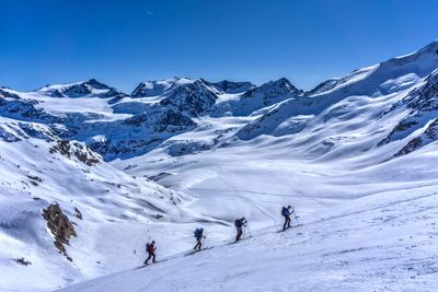 People walking on snowcapped mountain against sky