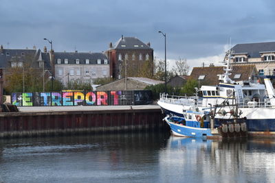 Boats moored at harbor against buildings in city