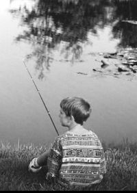 Boy sitting by lake