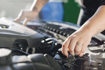 Cropped image of female mechanic opening car coolant