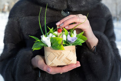Women's hands hold a small basket with handmade soap snowdrops.