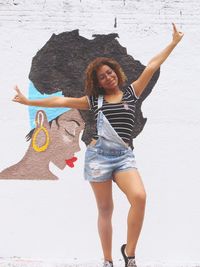 Portrait of young woman with arms raised on beach