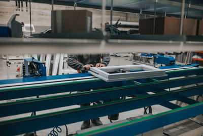 Low section of manual worker making window frame at factory