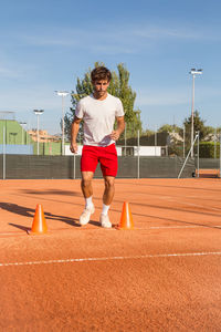 Full length of young man exercising at tennis court