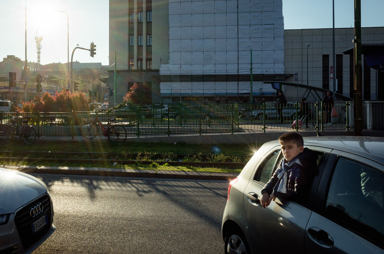 car, motor vehicle, mode of transportation, land vehicle, transportation, architecture, built structure, building exterior, city, nature, real people, sunlight, street, day, glass - material, building, child, outdoors, sky, people