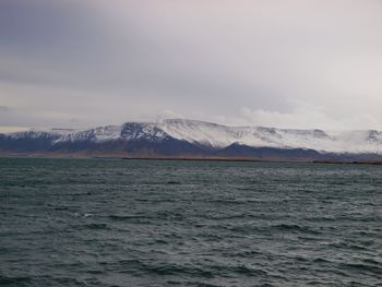 Scenic view of sea and snowcapped mountains against sky