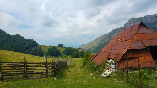 Scenic view of cottage and landscape and mountains against sky