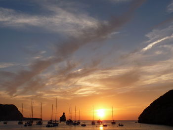 Sailboats on sea against sky during sunset