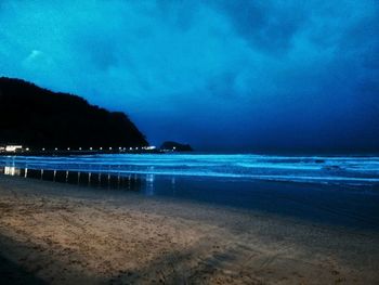 Scenic view of beach against sky at dusk