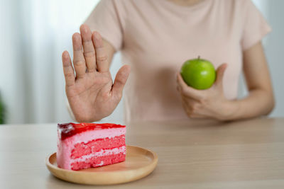 Midsection of person holding apple on table