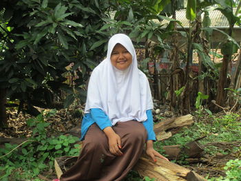 Portrait of young woman standing against plants