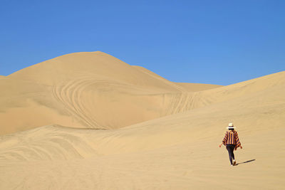 Woman walking up on to the amazing sand dunes of huacachina desert, ica region, peru, south america