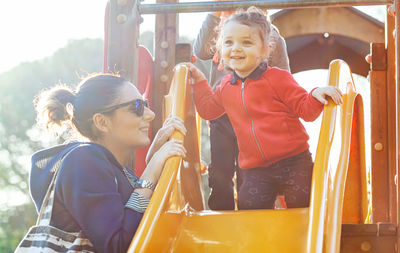 Aunt and nephew play on the slide at the park in a spring day.