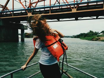 Woman with tousled hair standing in boat on river