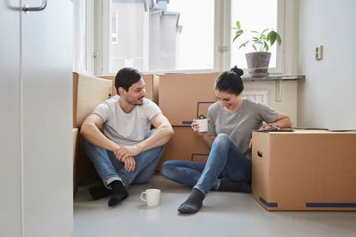 Smiling couple talking while enjoying coffee during moving house