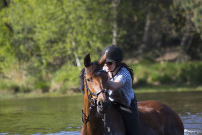 Smiling woman horseback riding in lake